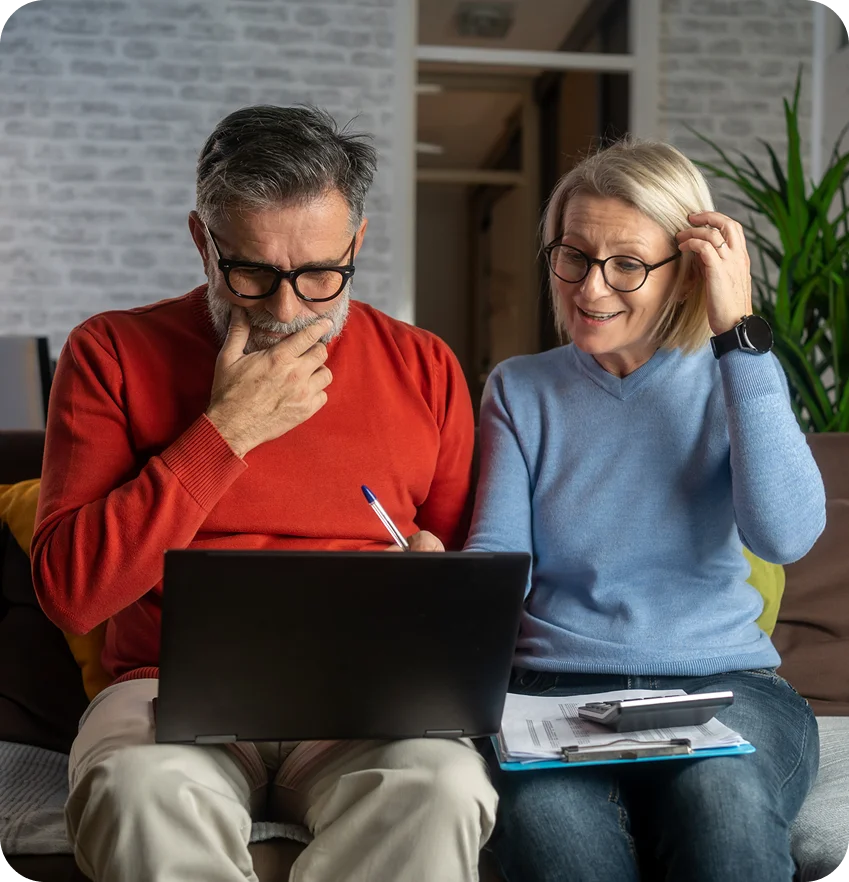 Older couple reviewing documents on laptop together.